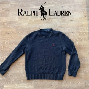 Marinblå tröja från Ralph Lauren - Säljer en stilren stickad blå tröja från Ralph Lauren med det klassiska röda broderade logotypen på bröstet. Tröjan är i fint skick. Skriv privat för exakta mått, fler bilder eller funderingar.🤗