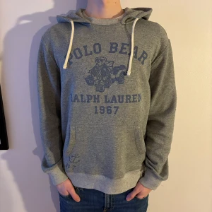 Grå hoodie från Polo Ralph Lauren - Säljer en grå hoodie från Polo Ralph Lauren med en cool Polo Bear-design på framsidan. Perfekt för en avslappnad stil! 🐻Nypris på Zalando är 2460kr. Inga deffekter, använd ett fåtal ggr endast. Kvitto finns!