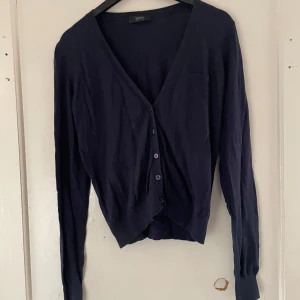 Mörkblå kofta från Esprit - Säljer en stilren mörkblå kofta från Esprit. Den har en v-ringad design med knappar framtill och långa ärmar. Perfekt för både vardag och lite finare tillfällen. Supermjuk och bekväm att ha på sig!