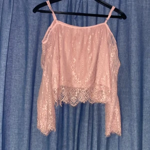 Rosa spetslinne - Säljer ett supergulligt rosa spetslinne med tunna axelband. Det är perfekt för sommardagar eller en festlig kväll. Linnet har en luftig passform och vackra spetsdetaljer som ger en romantisk känsla. Passar perfekt till jeans eller en kjol!