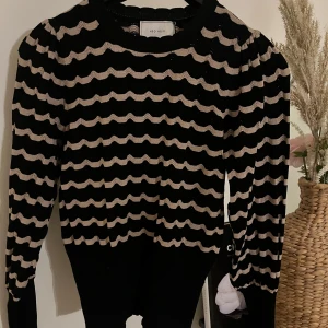 Neo Noir tröja - Säljer en superfin randig tröja från Neo Noir. Den har långa ärmar och ett vågigt guldigt mönster Perfekt för både vardag och fest! 🖤✨Använd 1 gång. Storlek 34 men stretchig så passar 36a också 🥰Nypris 749kr