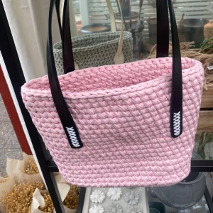Rosa flätad väska - Säljer en superfin rosa virkad väska med svarta läder handtag. Den är perfekt för sommarens alla äventyr och har en stabil läder botten med små metallfötter. Väskan är både snygg och praktisk!