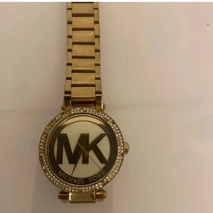 Guldfärgad klocka från Michael Kors - Säljer en snygg guldfärgad klocka från Michael Kors. Klockan har en glittrig ram runt urtavlan. Klockan fungerar fortfarande du bör bara lägga ett batteri i klockan. Några stendiamanter har ramlat av som man ser. Nypris runt över 2000