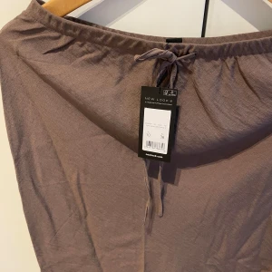 Brun kjol från New Look - Säljer en snygg brun kjol från New Look. Kjolen har en enkel design med resår i midjan och är perfekt för både vardag och fest. Den är i ett mjukt och bekvämt material som faller fint. Storlek 38
