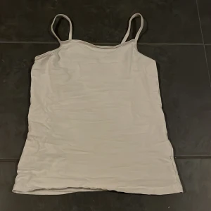 Vit linnetopp från H&M - Säljer en enkel och stilren vit linnetopp från H&M i storlek 146/152. Perfekt för sommardagar eller som ett basplagg i garderoben. Toppen har smala axelband och är i ett mjukt och bekvämt material. Passar både till vardags och festliga tillfällen.