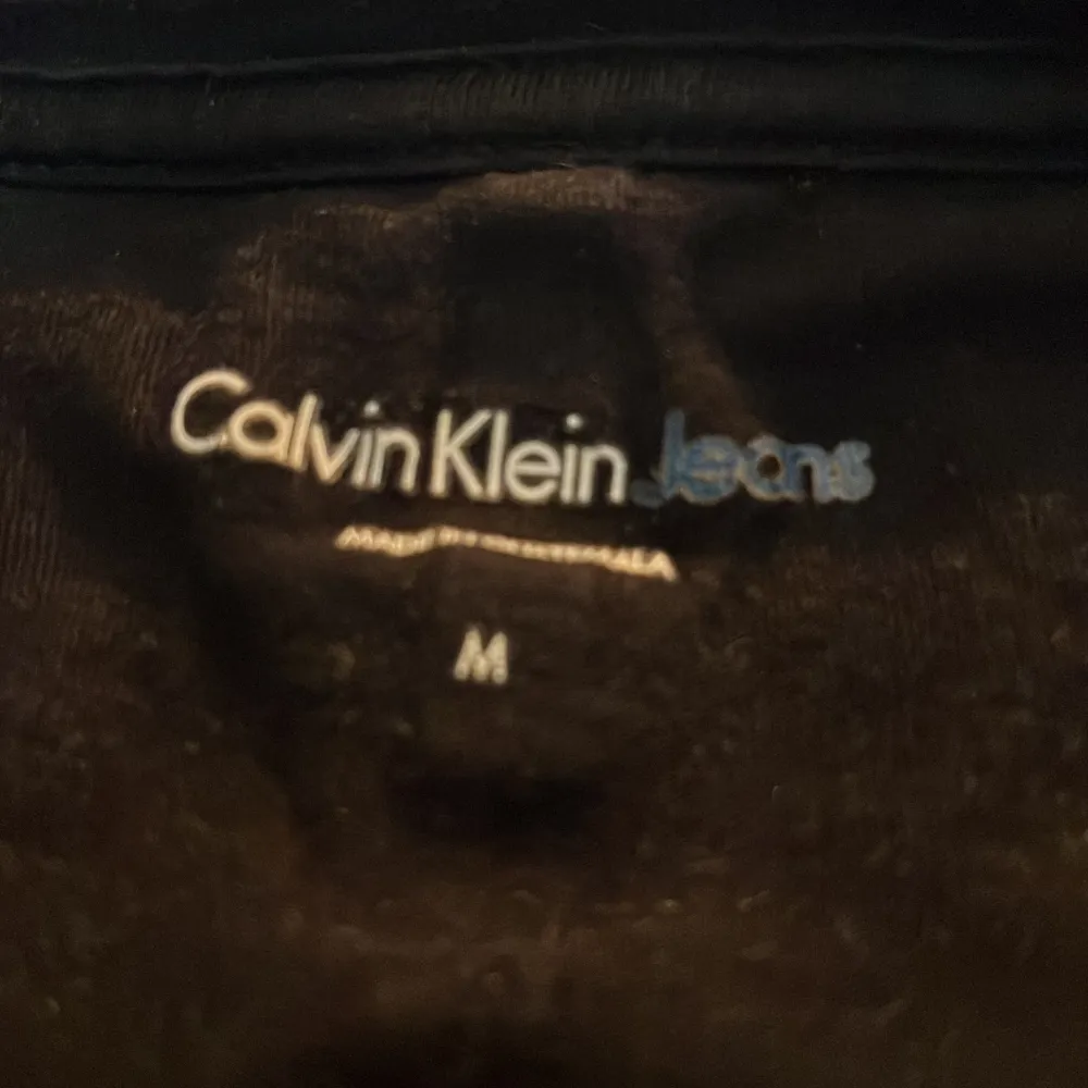 Säljer en snygg svart t-shirt från Calvin Klein Jeans i storlek M men sitter bättre på S! Den har en klassisk passform med korta ärmar och ett stort CK-logotryck på framsidan. Perfekt för en casual look eller att matcha med jeans för en stilren outfit. Tröjan kommer i bra skick 8/10 använd!. T-shirts.