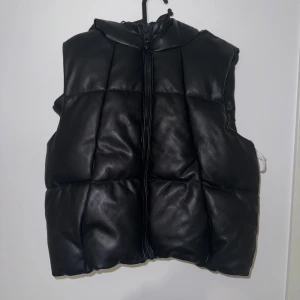 Svart quiltad dunväst - Säljer en snygg svart quiltad dunväst i skinnimitation. Storlek S 