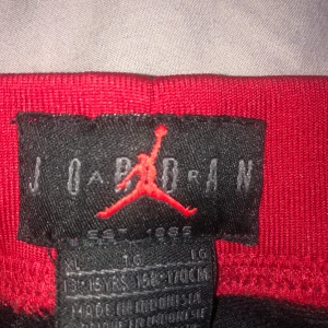 Vit och svart Jordan jacka - Säljer en snygg vit och svart Jordan jacka med det klassiska röda logotypen på ryggen. Jackan har en sportig stil med långa ärmar och är perfekt för både träning och vardag. Den är i mycket bra skick och redo för nya äventyr! 🏀