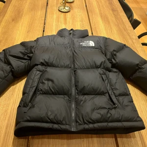 Svart pufferjacka från The North Face - Säljer en svart pufferjacka från The North Face i storlek XL för tonåringar men passar ca 160cm. Jackan är i mycket bra skick och perfekt för kalla vinterdagar. Jackan köptes i vintras men är knappt andvänd. Nypris ca 3000 men mitt pris är 1500. Men priset är inte hugget i Sten 🗿tveka inte att höra av sig vid minsta fundering ✌️👌