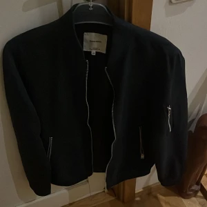 Svart bomberjacka från Jack & Jones - Säljer en mörkblå bomberjacka från Jack & Jones i storlek XS. Jackan har en dragkedja framtill och två fickor med dragkedjor. Perfekt för höst och till vinter.