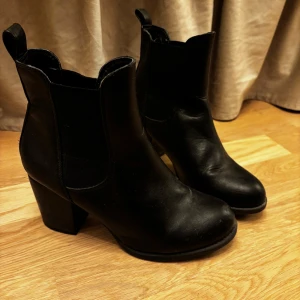 Svarta Chelsea boots - Snygga svarta Chelsea boots i skinn från VOX Shoes. De har en bekväm klack och elastiska paneler på sidorna för enkel på- och avtagning. Perfekta för både vardag och fest!
