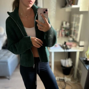 Grön stickad kofta med dragkedja - Säljer en supermysig grön stickad kofta med dragkedja framtill. Perfekt för höst och vinter, den har långa ärmar och en skön passform. Koftan är i bra skick och passar perfekt för att hålla sig varm och stilren. Perfekt för lager-på-lager-look! 🍂Iprincip oanvänd! nypris ca 600kr