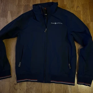 Sail Racing jacka - Säljer en snygg mörkblå jacka från Sail Racing. Jackan har en stilren design med logga på bröstet och ryggen, Perfekt för höst och vår!😀storlek s/xs