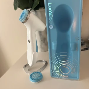LumiSpa IO ansiktsrengöringsborste - Säljer en ageLoc LumiSpa IO ansiktsrengöringsborste i vitt och blått. Den har en ergonomisk design med en utbytbar borsthuvud för effektiv rengöring. Perfekt för daglig hudvård och ger en fräsch känsla. Du kan läsa mer om produkten och kika på vad en ny kostar på nuskins hemsida, filtrera enligt produkten ageLOC Lumispa IO. Laddningskabel kommer med, även stället den står i som jag köpte separat. 