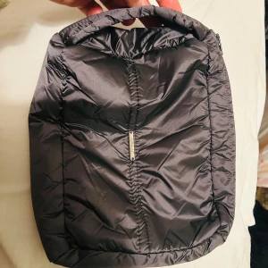 Mörkgrå sminkväska från Anorak - Snygg och praktisk mörkgrå sminkväska från Anorak. Tillverkad i syntetmaterial med en quiltad design och dragkedja för säker förvaring. Perfekt för att bära smink och smycken eller andra viktiga prylar.