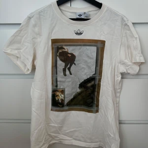 Beige t-shirt från Adidas med tryck - Säljer en vit t-shirt från Adidas med ett unikt tryck på framsidan. Använd ett fåtal gånger 🌸
