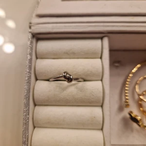 Silverfärgad ring med knutdetalj - Elegant och stilren ring i silverfärg med en unik knutdetalj på framsidan. Perfekt för att ge en subtil men chic touch till din outfit. Passar bra till både vardag och speciella tillfällen. Ny pris ca 100kr, aldrig använd. 