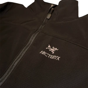 Arc'teryx - Snygg svart soft shell-jacka från Arc'teryx med dragkedja och broderad logga på bröstet. Jackan har en stilren design med långa ärmar och hög krage. Perfekt för en minimalistisk look. Storlek M. Bra skick. Passar perfekt till våren 