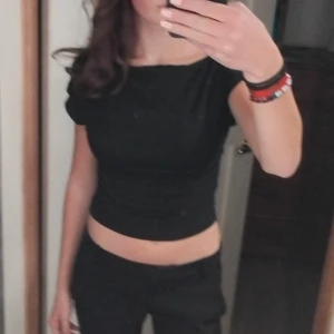 Svart croppad topp - Snygg svart croppad topp med korta ärmar. Perfekt för en stilren look. Toppen har en tight passform som framhäver figuren.