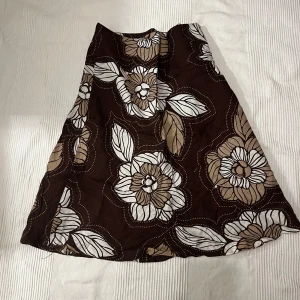Brun blommig kjol - Snygg brun kjol med stort blommönster. Kjolen är köpt secondhand och är en gammal hm modell. Skulle säga att den passar bäst för en s/m🌟🌟