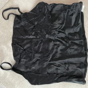 Svart satinlinne från Zara - Snyggt svart satinlinne från Zara med smala axelband. Perfekt för en stilren look. Linnet är croppat och har en glansig finish som ger en lyxig känsla.