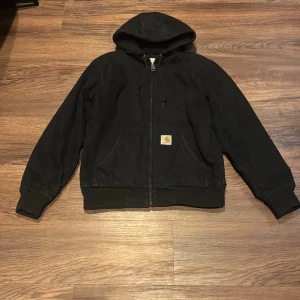 Svart jacka från Carhartt - Säljer en svart jacka från Carhartt. Jackan har en klassisk design med Carhartt-logga på framsidan och praktiska fickor.