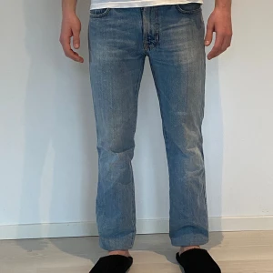 Nudie jeans slim jim - Snygga blå jeans med en klassisk straight passform. De har broderade detaljer på bakfickorna som ger en unik touch. Perfekta för en avslappnad stil. Storlek 30/32
