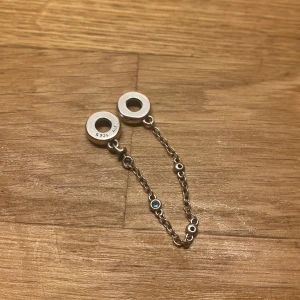 Silverfärg berlock med blå detaljer - Elegant silverfärgat armband med kedja och runda länkar. Armbandet har små blå detaljer som ger en fin kontrast. Perfekt för att lägga till en subtil färgklick till din outfit.