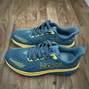 Blå och gula sneakers från Noka - Snygga blå sneakers från Noka med gula detaljer och snörning. Perfekta för en sportig look med en bekväm passform. Skorna har en modern design med mönstrade detaljer på ovansidan.