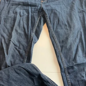 Blå jeans från Tommy Hilfiger - Snygga blå jeans från Tommy Hilfiger med klassisk design. De har en normal passform och är tillverkade i bomull med en liten del elastan för extra komfort. Perfekta för en stilren look.