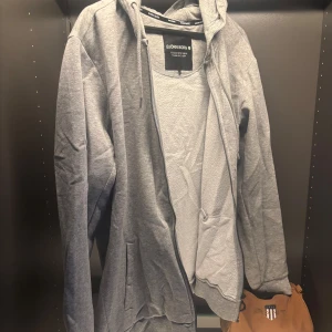 Grå hoodie från Björn Borg - Säljer en stilren grå hoodie från Björn Borg. Den har en dragkedja framtill och en praktisk huva. Perfekt för en avslappnad look. 🩶