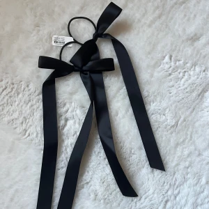 Svarta hårband med rosetter - Två eleganta svarta hårband med långa rosetter. Perfekta för att ge en stilfull touch till din frisyr. Passar både till vardag och festliga tillfällen.