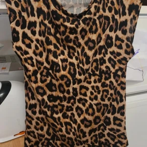 Leopardmönstrad ärmlös topp - Snygg leopardmönstrad topp i beige och svart. Den är ärmlös och har en rund halsringning. Perfekt för att ge en vild touch till din outfit!