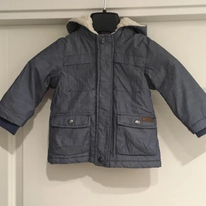 Fin Blå grå  vinterjacka med teddyfoder/74 - Säljer en mysig blå vinterjacka med teddyfoder. Jackan har en huva och stängs med knappar.. Perfekt för kalla dagar! 💙