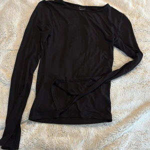 Svart långärmad topp - Snygg och enkel svart långärmad topp. Perfekt basplagg med en tight passform som funkar till det mesta. Tillverkad i ett mjukt och stretchigt material för extra komfort. Med en liten detalj som en slit på slutet utav armen 