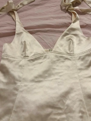 Gul korsettopp med knytband - Snygg vit korsettopp med knytband på axlarna. Toppen har en figurnära passform och markerade sömmar framtill för en trendig look. Perfekt att styla med jeans eller kjol för en chic outfit.