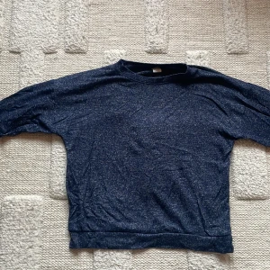 Mörkblå långärmad tröja - En enkel och stilren mörkblå långärmad tröja med melerad effekt. Tröjan har rund halsringning och är tillverkad i ett mjukt och stretchigt material. Perfekt för lager-på-lager. 💕👌