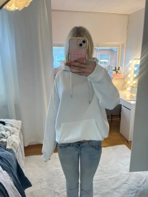Vit oversized hoodie med ficka - Säljer en vit oversized hoodie med stor magficka och dragsko i huvan. Hoodien har en avslappnad passform och är gjord i mjukt material, perfekt för en chill och stilren look. Passar till jeans eller mjukisbyxor.