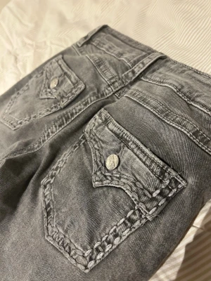 Grå jeans från Gina Tricot - Säljer ett par grå jeans från Gina Tricot med snygga detaljerade bakfickor och silvriga knappar. Storlek 152 