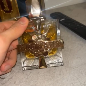 Aromatix French Avenue X xandal - Lyxig parfym från Aromatix med en unik, fyrkantig glasflaska och guldfärgade detaljer. Flaskan har en elegant design med geometriska former och ett stort guldfärgat band med texten 'Aromatix French Avenue' framtill. Perfekt för dig som gillar exklusiva dofter. 98/100 kvar