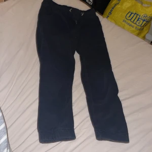 Svarta mjukisbyxor med dragsko - Säljer ett par svarta mjukisbyxor med dragsko i midjan och raka ben. Byxorna har bred resår i midjan och är gjorda i mjukt sweatshirtmaterial. Perfekta för chill dagar eller när du vill vara bekväm.