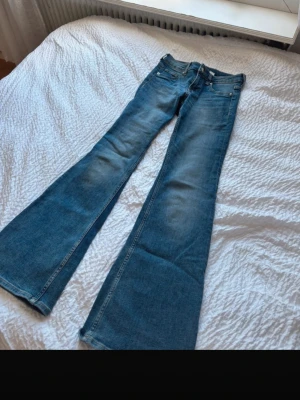 Blå bootcut jeans  - Säljer ett par blå bootcut jeans med utsvängda ben. Jeansen har en snygg tvätt med lätt slitning framtill och bakfickor. I storlek 34! Skriv för bilder med dem på!❣️