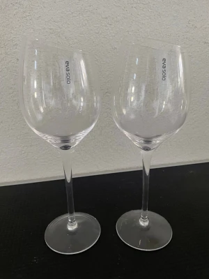 Två vinglas från Eva Solo - Säljer två eleganta vinglas från Eva solo. Glasen är genomskinliga med klassisk rund kupa och lång smal fot. Perfekta för att njuta av vin med stil. Passar både till middagsbordet och som present. Syrah Modellen, dom är inte använda men upptagna från orginalförpackning!