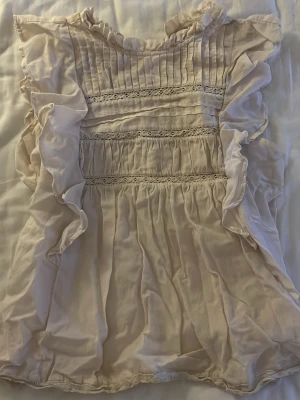 Ljusbeige volangblus Holly & Whyte - Supersöt ljusbeige blus från Holly & Whyte by Lindex med volangdetaljer längs ärmarna och spetsinslag framtill. 