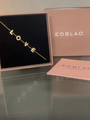 Guldigt LOVE-armband från Edblad - Snyggt armband i guldton från Edblad med bokstäverna L O V E som hänger på en tunn kedja. Perfekt accessoar för dig som vill ha något personligt och stilrent. Kommer i originalask med tillhörande kort. Skicka gärna prisförslag eller frågor 