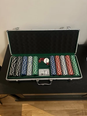Poker set - Säljer ett komplett poker set i en silverfärgad aluminiumväska. Innehåller pokerchips i svart, blå, vit, röd och grön färg, en kortlek, röda tärningar och en dealer-knapp. Perfekt för pokerkvällar med vänner. Väskan har skumfoder på insidan och praktiskt handtag.