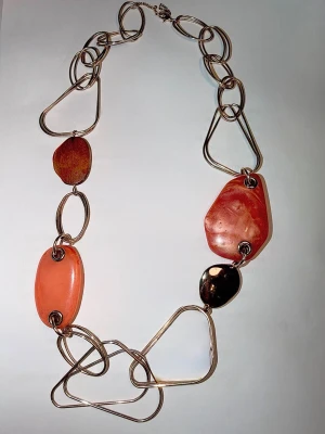 Boho halsband - Smycket kombinerar stora, polerade naturstenar i varma toner av orange, rost och brunt med asymmetriska metallänkar.  Längd: ca 61,5 cm. Stil: Vintage-look, modern bohemisk, station necklace. Skick: Gott skick Material: Naturstenar och metall.