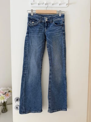 Blå bootcut jeans med låg midja - Ett par klassiska blå bootcut jeans med låg midja och fem fickor.