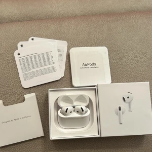 Apple AirPods 4 med laddningsetui - Säljer ett par vita Apple AirPods 4 med aktiv brusreducering och trådlöst laddningsetui. Hörlurarna har en stilren och kompakt design i plast och levereras i originalförpackning med tillhörande manualer.