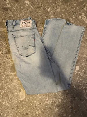 Ljusblå slitna jeans från Replay - Säljer ett par ljusblå jeans från Replay med skinny fit och slitningar framtill för en trendig look. Klassisk femficksmodell med Replay-lapp bak i midjan. Perfekta för dig som gillar en avslappnad men ändå stilsäker stil.  Har hål på framsidan!